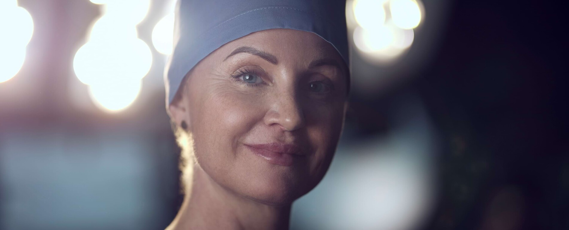 Nahaufnahme von Frau Dr. Pia Rademacher im OP-Saal mit heller Deckenbeleuchtung im Hintergrund.