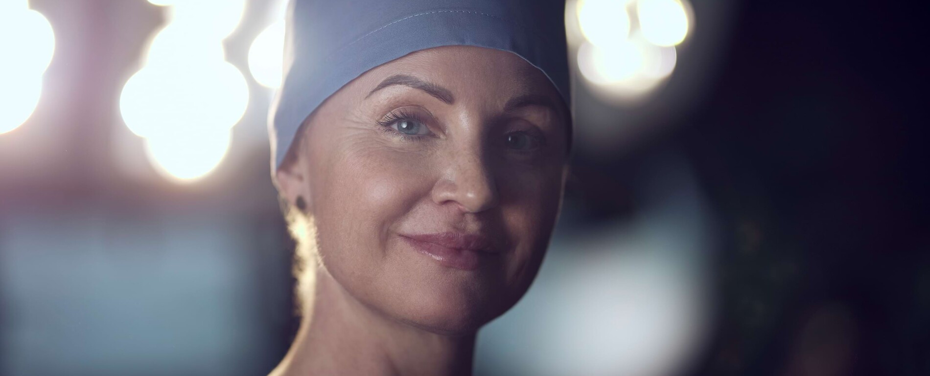 Nahaufnahme von Frau Dr. Pia Rademacher im OP-Saal mit heller Deckenbeleuchtung im Hintergrund.