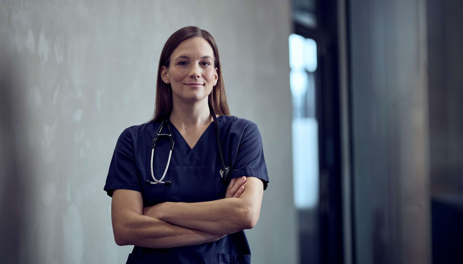 Frau Dr. Kl&uuml;ser steht mit verschr&auml;nkten Armen im Gang.