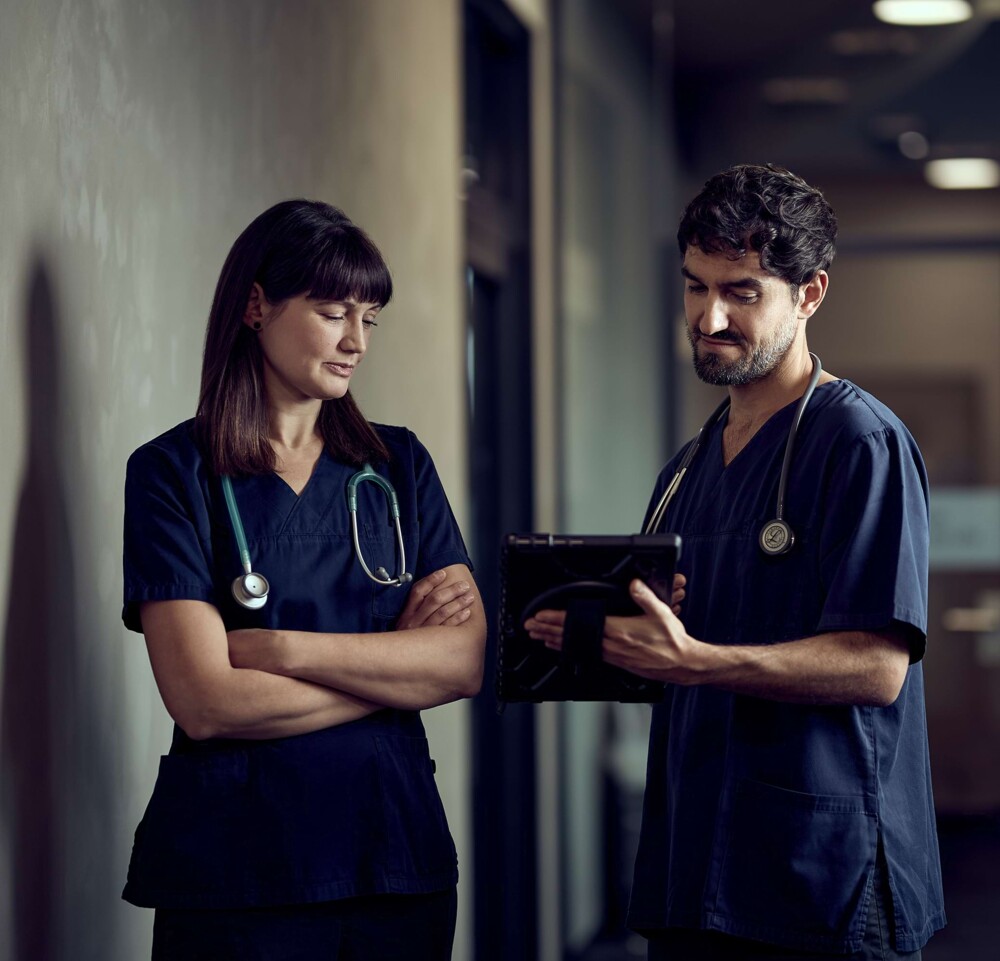 Eine Tierarzthelferin und ein Tierarzthelfer betrachten gemeinsam ein Tablet.