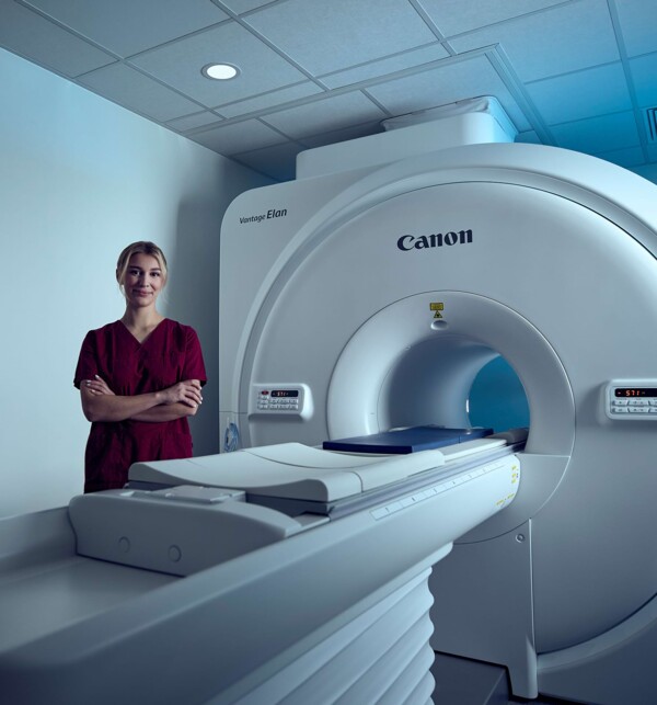 Eine Tierarzthelferin steht neben einem Computertomografen.