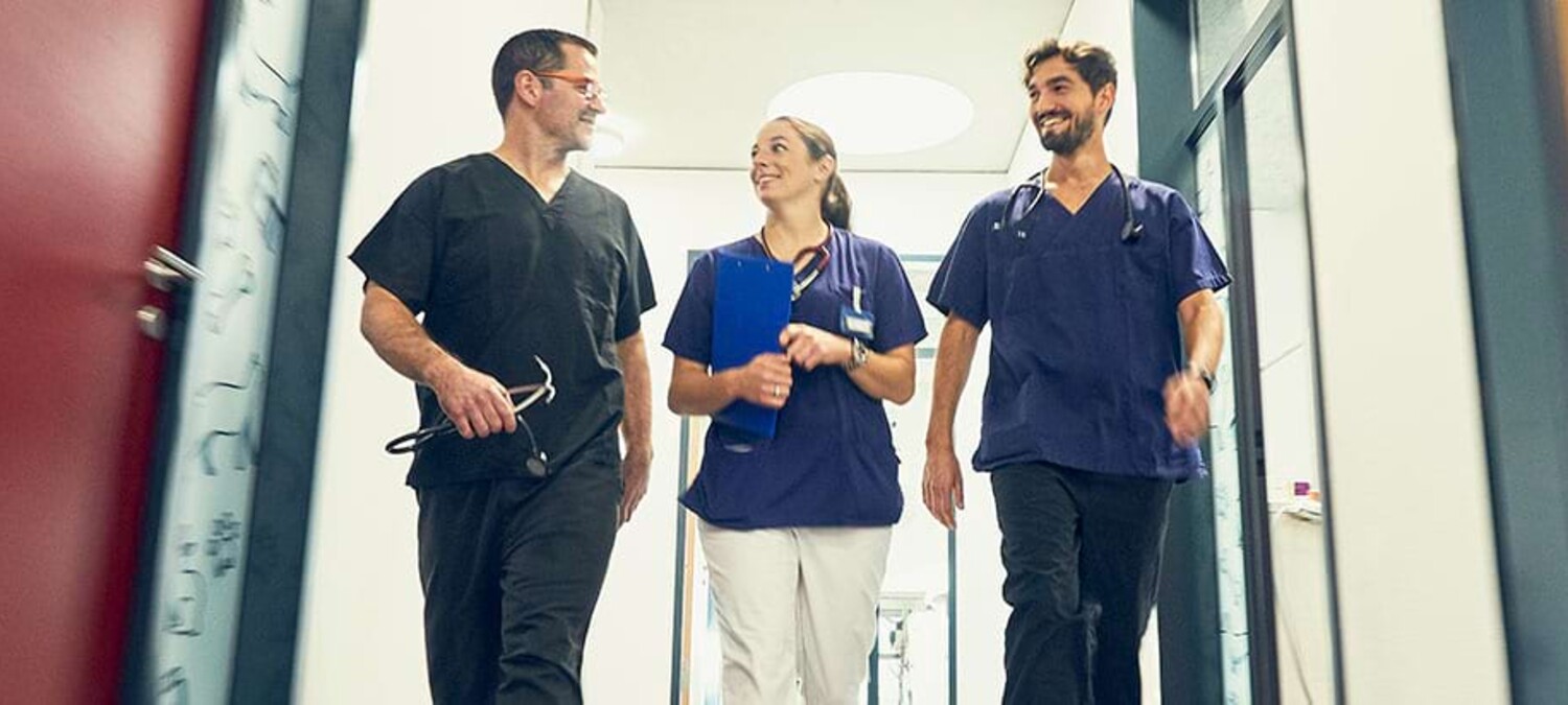 Dres. Lautersack und Ruben Jimenez laufen gemeinsam &uuml;ber den Flur der Klinik.